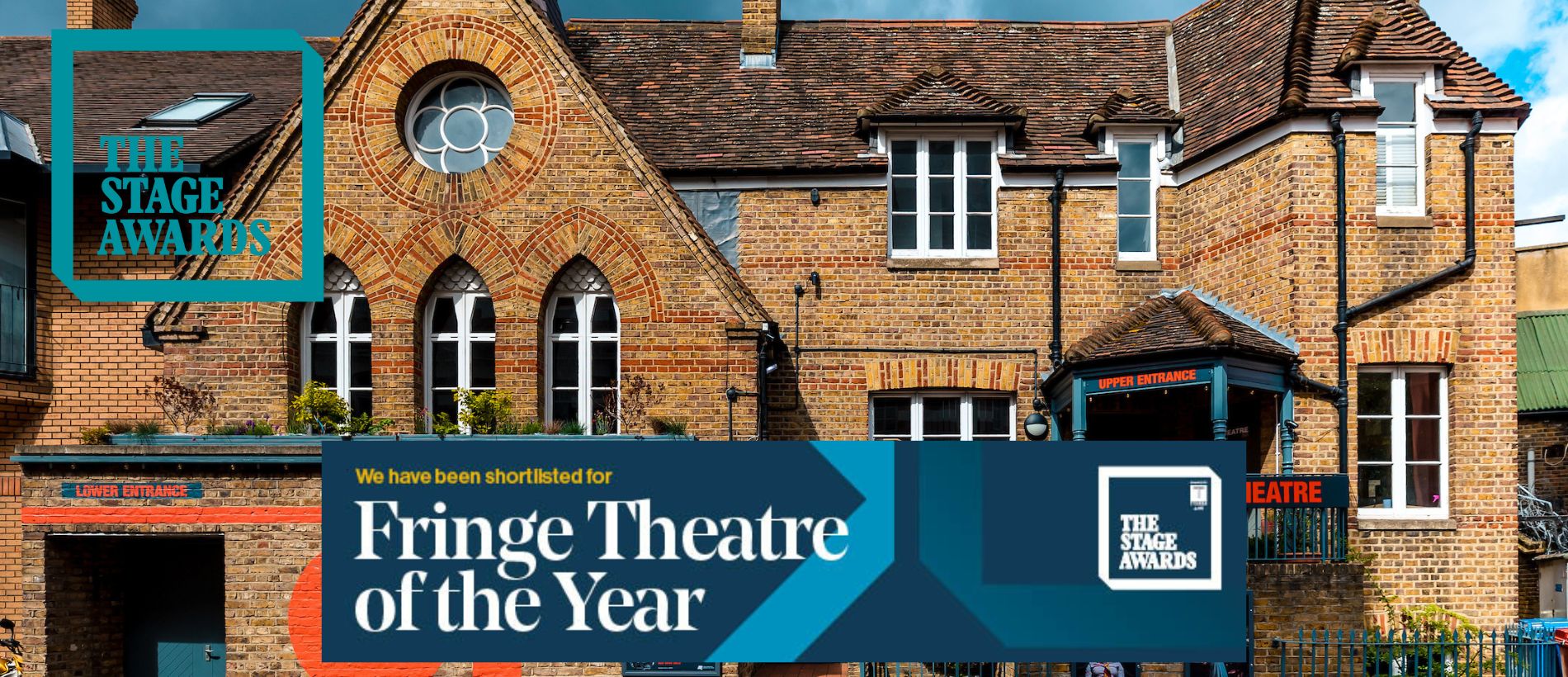 A photo of the Orange Tree Theatre with the Stage Awards teal logo and a The Stage Awards badge reading 'We have been shortlisted for Fringe Theatre of the Year'. The OT building is a brick building, with a large, red, OT symbol painted on the side and a set of stairs leading to the first floor entrance.